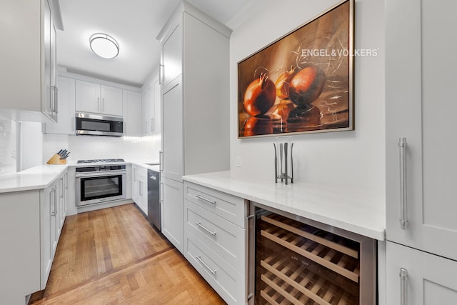 kitchen with tasteful backsplash, beverage cooler, light countertops, appliances with stainless steel finishes, and white cabinets