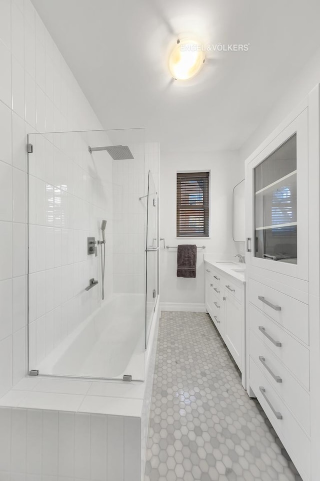 bathroom with baseboards, vanity, and a tile shower