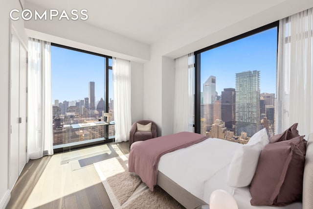 bedroom featuring a view of city and wood finished floors