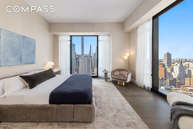 bedroom with a city view and dark wood-type flooring