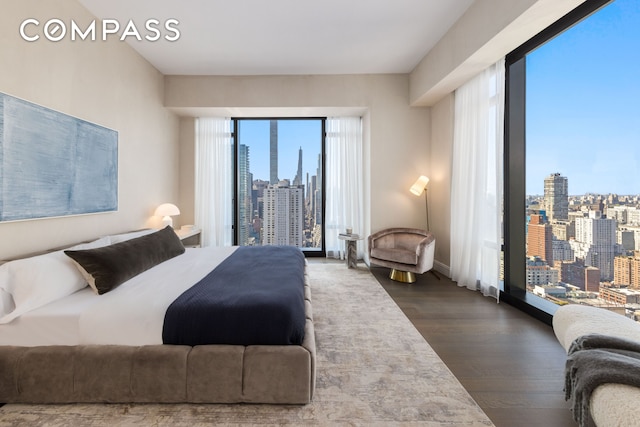 bedroom featuring a view of city, baseboards, and dark wood finished floors