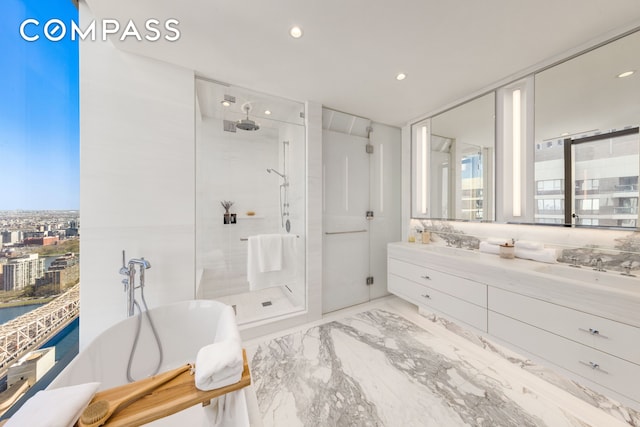 bathroom featuring double vanity, a freestanding tub, a shower stall, and marble finish floor