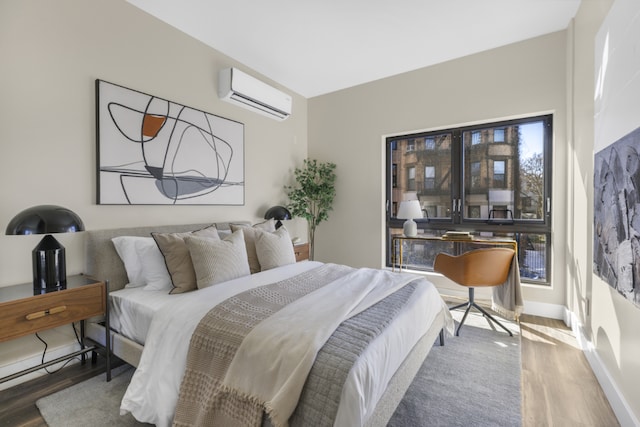 bedroom with a wall mounted air conditioner and hardwood / wood-style floors