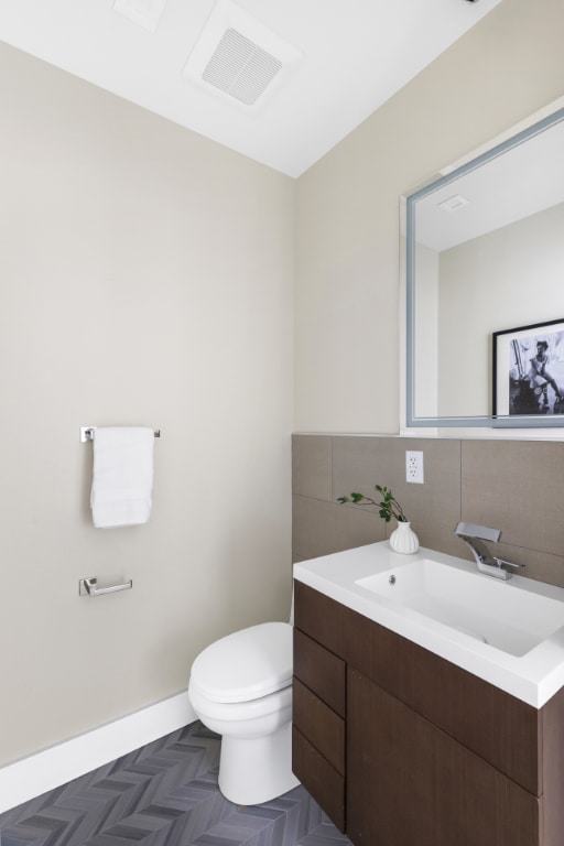 bathroom featuring vanity, toilet, and decorative backsplash