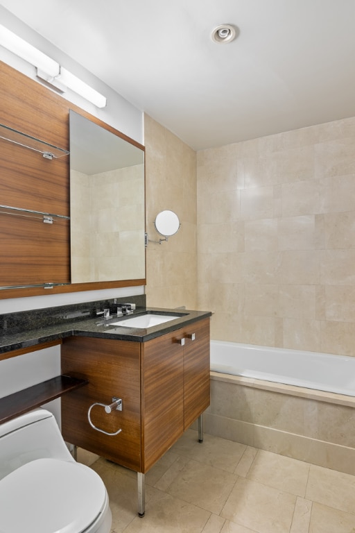 full bathroom with a tub to relax in, tile walls, toilet, vanity, and tile patterned flooring