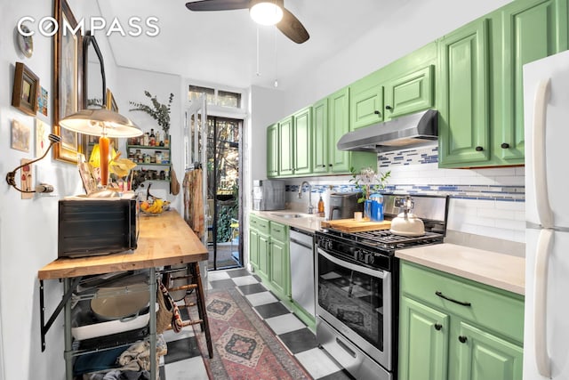 kitchen featuring dark floors, under cabinet range hood, light countertops, appliances with stainless steel finishes, and green cabinetry