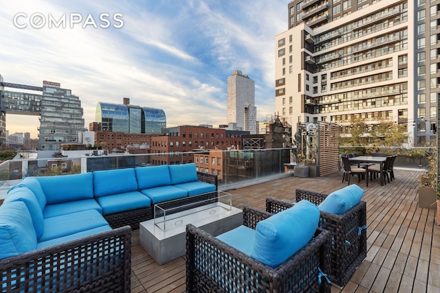 wooden deck featuring outdoor dining space, a view of city, and an outdoor living space with a fire pit