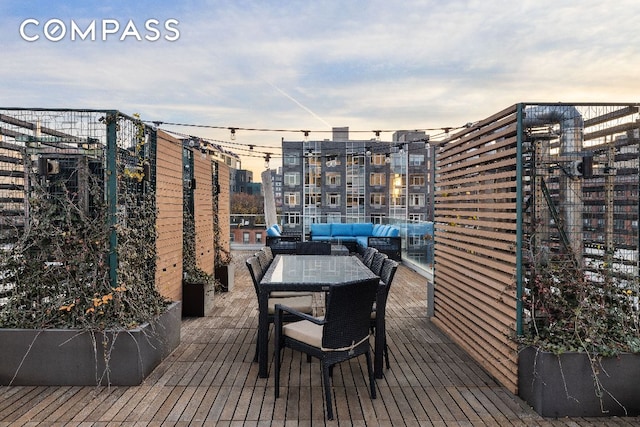 deck at dusk featuring outdoor lounge area, a view of city, and outdoor dining area