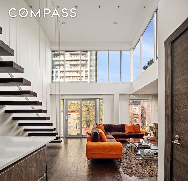 living area with a towering ceiling, stairway, and wood finished floors