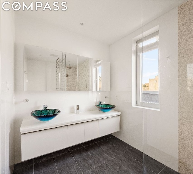 bathroom featuring vanity, tile walls, a shower, and tile patterned floors