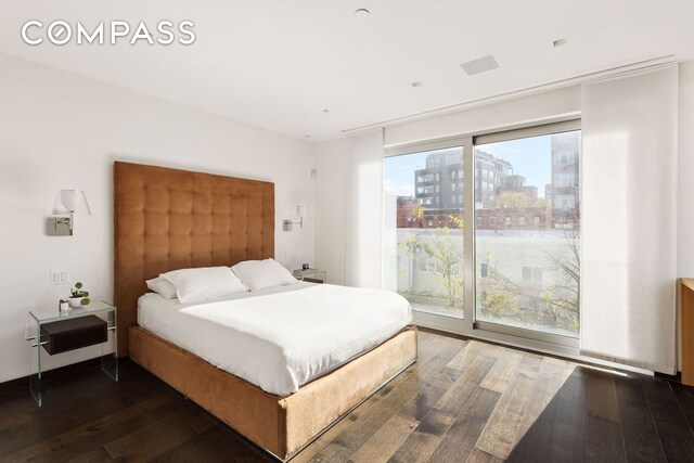 bedroom with dark wood-style floors, access to outside, a view of city, and multiple windows