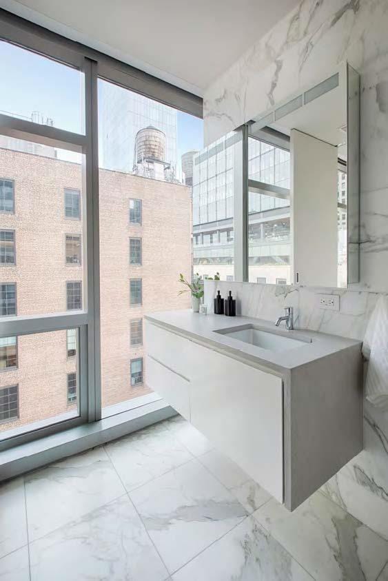 bathroom with marble finish flooring, expansive windows, a sink, and a view of city