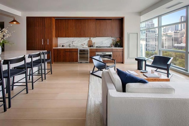 living room featuring sink, a wealth of natural light, light hardwood / wood-style flooring, and wine cooler