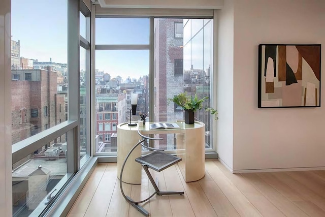 dining space with a view of city, baseboards, floor to ceiling windows, and light wood finished floors