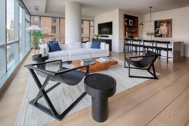 living room featuring a wall of windows and light hardwood / wood-style flooring