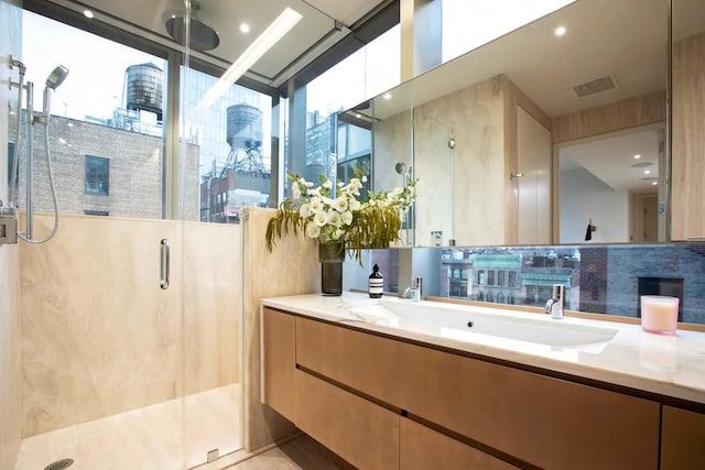 full bathroom featuring visible vents, a healthy amount of sunlight, a shower stall, and vanity