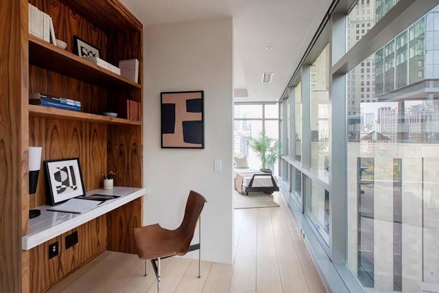 home office featuring floor to ceiling windows and light hardwood / wood-style floors