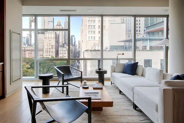 living area with a view of city, a wall of windows, and wood finished floors