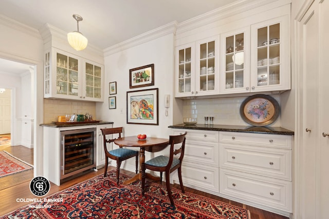 bar featuring wine cooler, white cabinetry, dark stone counters, and crown molding