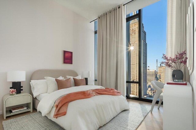 bedroom featuring multiple windows, access to exterior, a wall of windows, and light hardwood / wood-style flooring