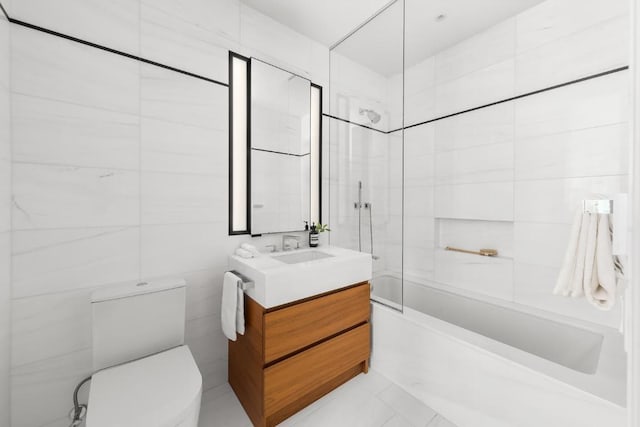 full bathroom featuring tiled shower / bath, tile walls, vanity, and toilet