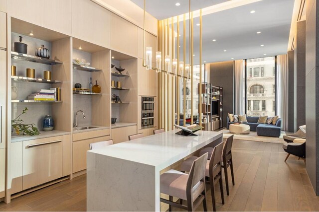 kitchen with pendant lighting, sink, a breakfast bar area, a center island, and light hardwood / wood-style flooring