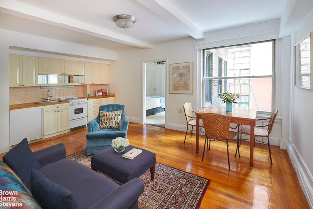 living room with sink, light hardwood / wood-style flooring, and beam ceiling