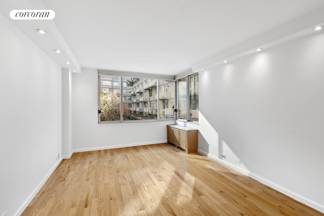 empty room featuring light wood-type flooring, visible vents, baseboards, and recessed lighting