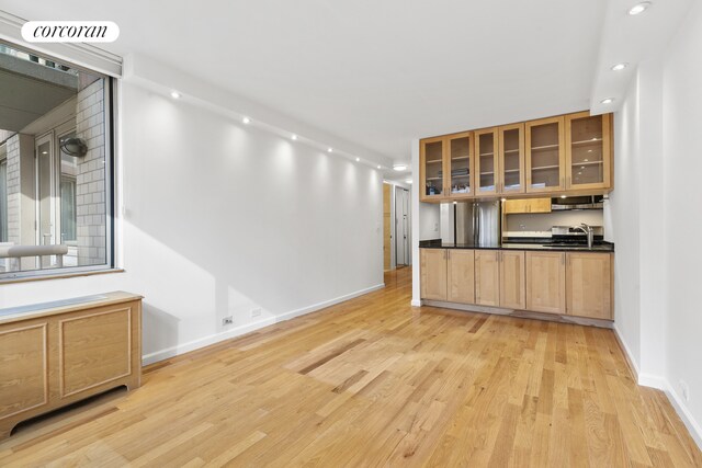 kitchen with dark countertops, light wood-style floors, visible vents, and glass insert cabinets