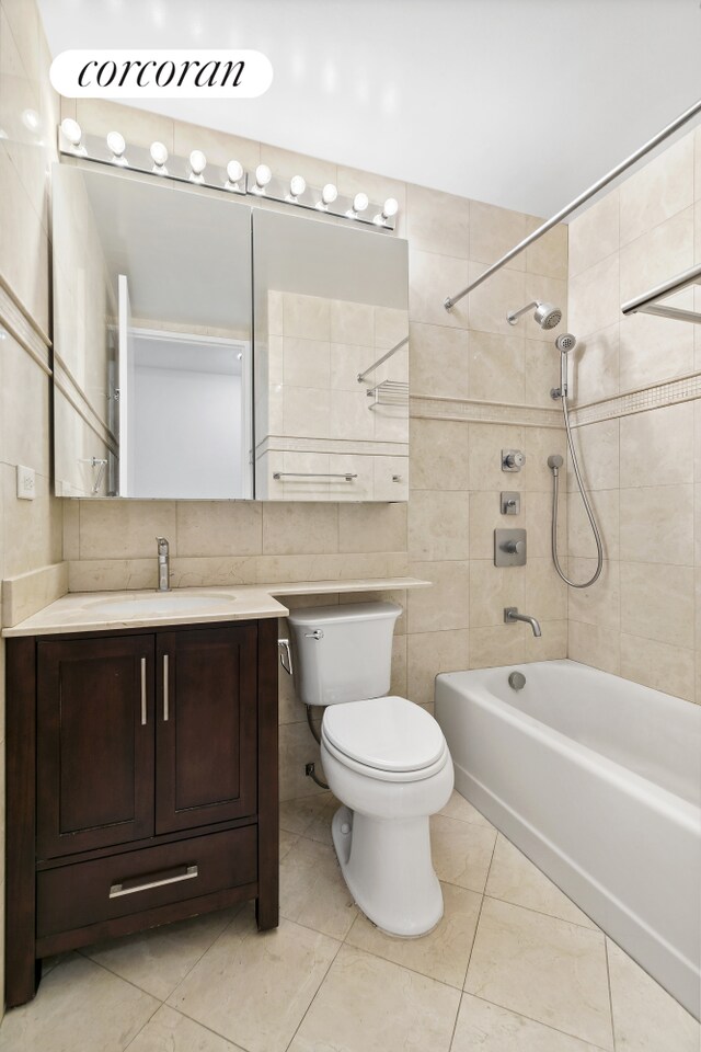 bathroom with tile walls, toilet, tub / shower combination, vanity, and tile patterned flooring