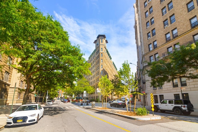 view of road featuring sidewalks, street lighting, traffic signs, and curbs