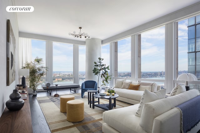 living area with a water view, visible vents, an inviting chandelier, and wood finished floors