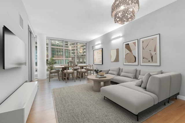 living room with light wood-type flooring, a chandelier, and a wall of windows