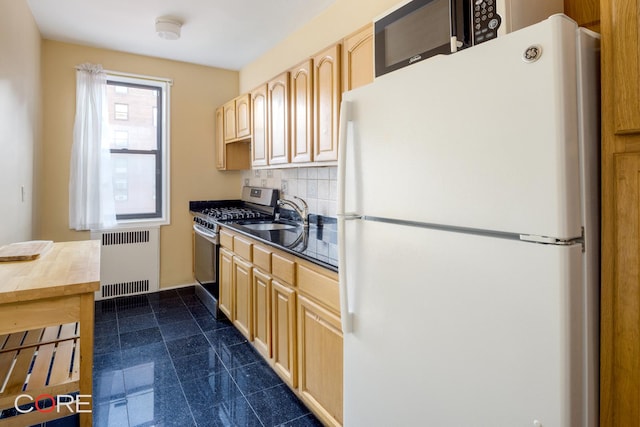 kitchen featuring freestanding refrigerator, radiator, a sink, stainless steel gas stove, and light brown cabinets