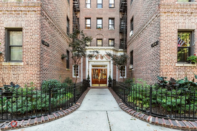 doorway to property with french doors, fence, and brick siding