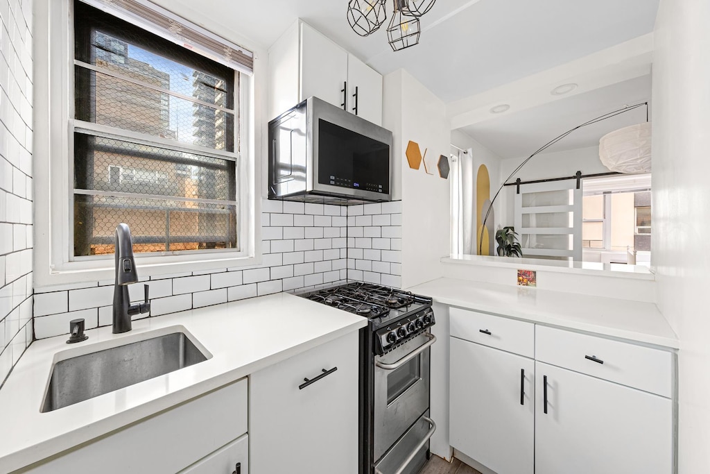 kitchen with stainless steel appliances, a wealth of natural light, a sink, and decorative backsplash