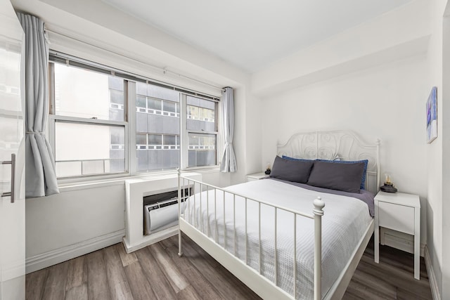 bedroom with a wall unit AC and wood finished floors