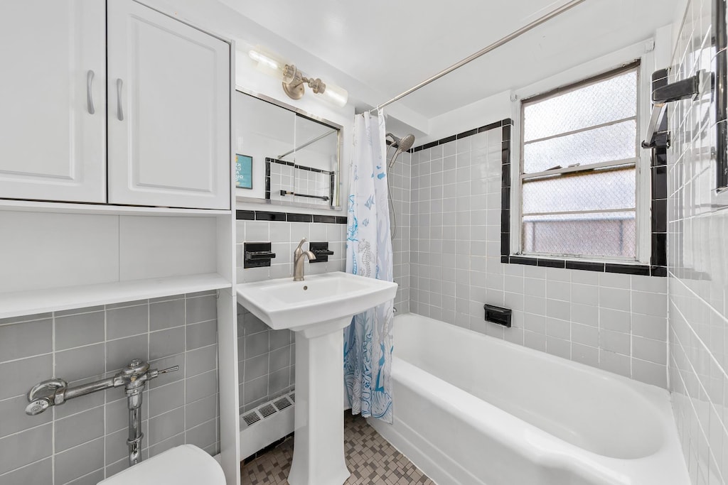 full bathroom with toilet, shower / tub combo, and tile walls