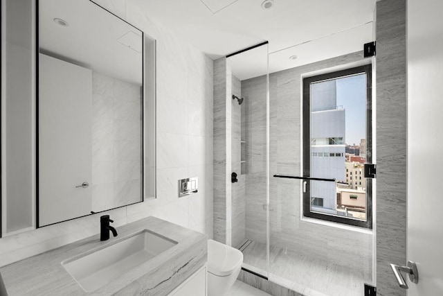 bathroom with toilet, a shower stall, tile walls, and vanity