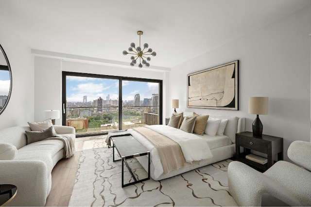 bedroom featuring an inviting chandelier, light wood-style flooring, and a view of city