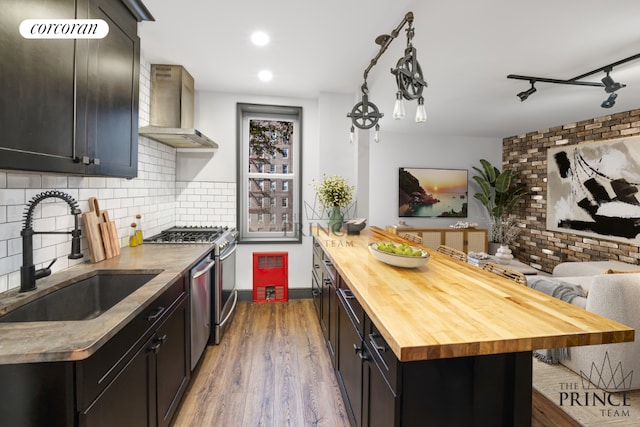 kitchen with wall chimney range hood, sink, stainless steel range with gas cooktop, and wooden counters