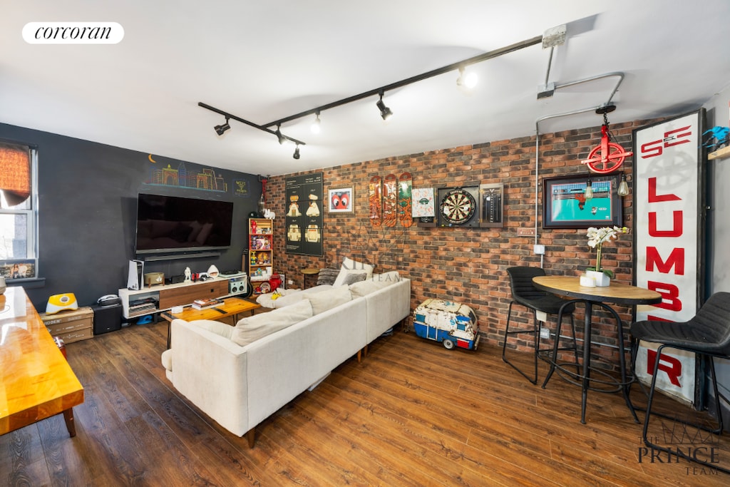 living room featuring brick wall, dark hardwood / wood-style floors, and rail lighting