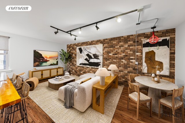 living room featuring brick wall, dark hardwood / wood-style flooring, and rail lighting