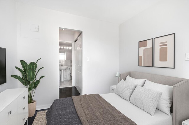 bedroom with dark wood-type flooring and connected bathroom