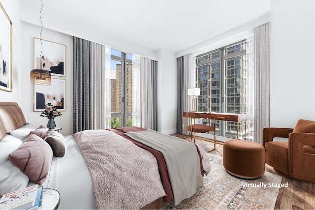 bedroom featuring expansive windows, a chandelier, wood-type flooring, and multiple windows