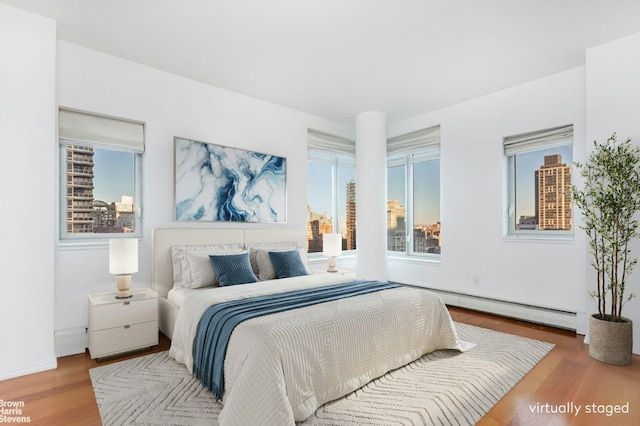 bedroom with hardwood / wood-style flooring and baseboard heating