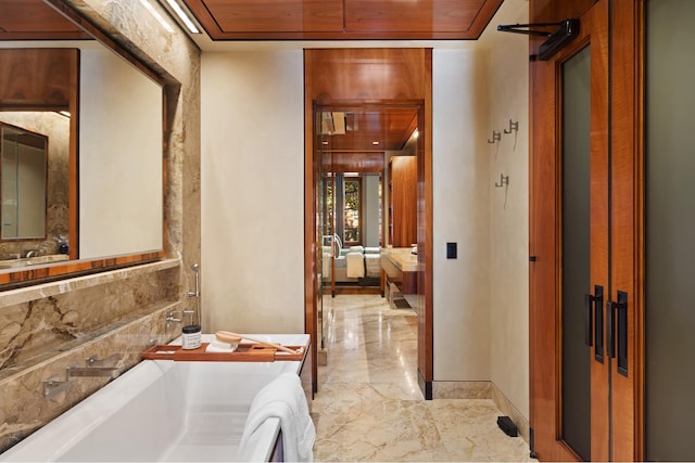 ensuite bathroom featuring wood ceiling, a soaking tub, marble finish floor, and ensuite bath