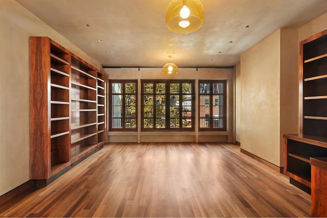 interior space with built in features, baseboards, and wood finished floors