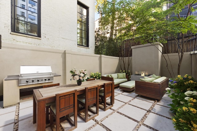 view of patio with an outdoor hangout area, an outdoor kitchen, a grill, and fence