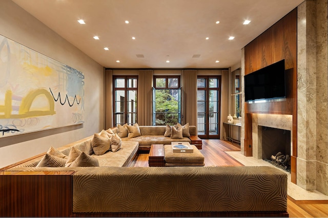 living room featuring a fireplace with flush hearth, recessed lighting, and light wood-style flooring